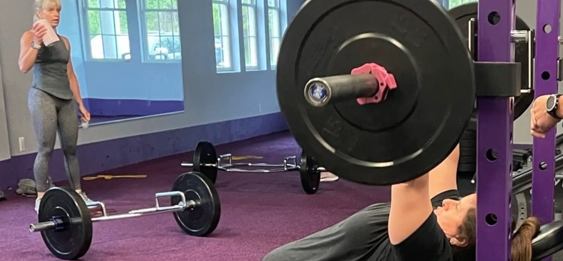 Woman performing an incline barbell bench press exercise in a gym